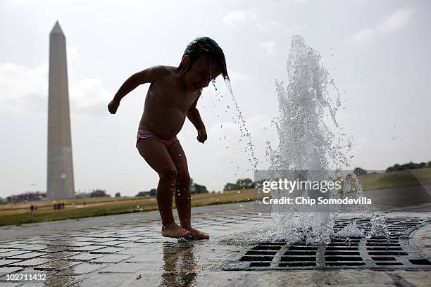 Two-year-old Carmen Brumos of Valencia, Spain, lowers her head into a jet of water near the Washington Monument on the National Mall July 8, 2010 in...