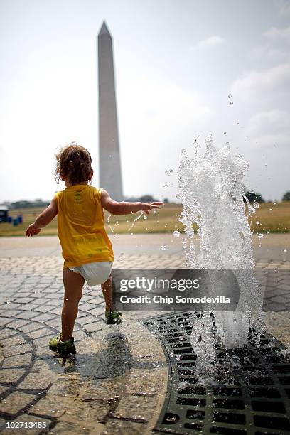 One-year-old Lukas Brumos Karrass of Raliegh, North Carolina, runs through a jet of water near the Washington Monument on the National Mall July 8,...