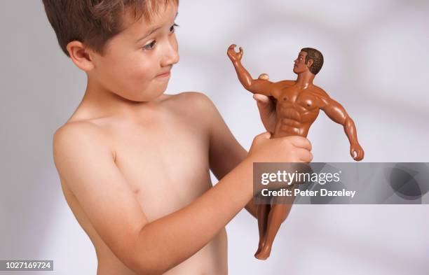 young boy admiring male doll's muscles - body dysmorphia stock pictures, royalty-free photos & images