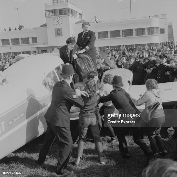 British pop rock group The Hollies escorted by the police as they arrive at Shoreham Airport, Brighton UK, 27th April 1964.