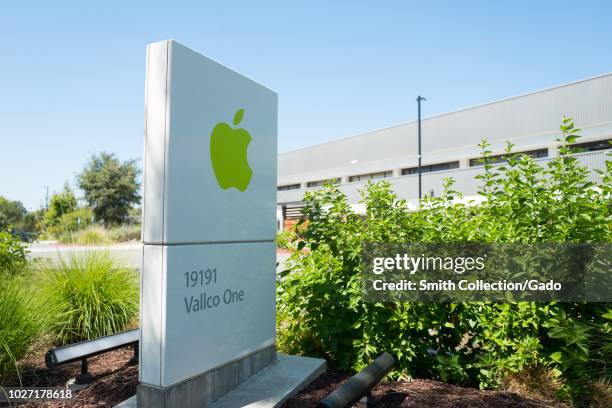 Sign with logo in green color, with facades of buildings in background, near the headquarters of Apple Computers in the Silicon Valley, Cupertino,...