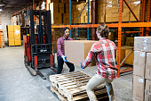 Two warehouse workers preparing to lift a heavy box together