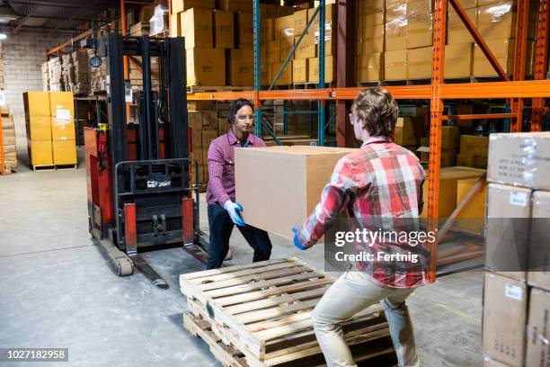 two warehouse workers preparing to lift a heavy box together - retrieving imagens e fotografias de stock