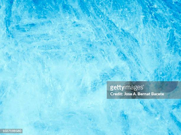 full frame of the textures formed of a block of cracked ice, on a soft blue background. - ice texture foto e immagini stock
