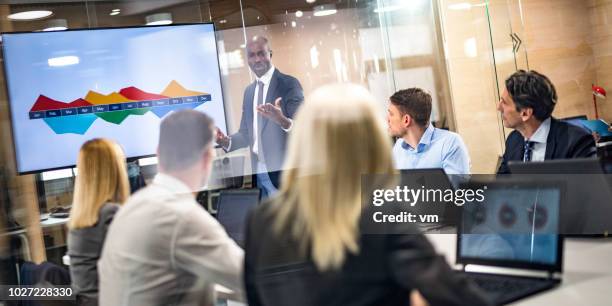 african-american businessman giving presentation to colleagues - finance report stock pictures, royalty-free photos & images