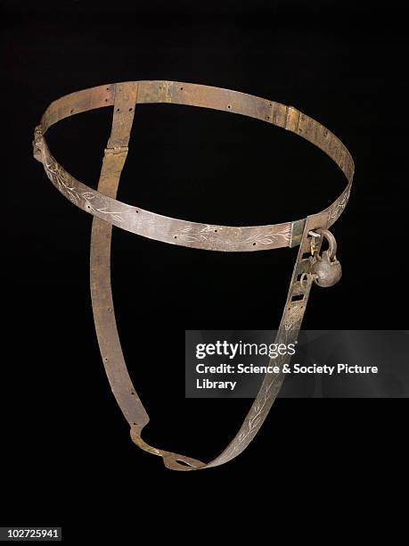 Iron chastity belt complete with padlock. Iron chastity belt complete with padlock. Front view of whole obejct against black background.