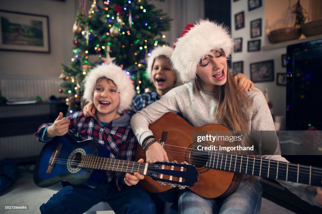 Children singing Christmas carols near Christmas tree