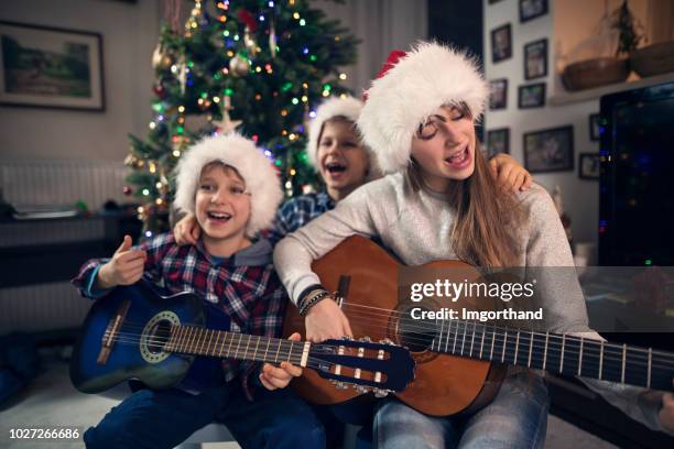 children singing christmas carols near christmas tree - family singing stock pictures, royalty-free photos & images