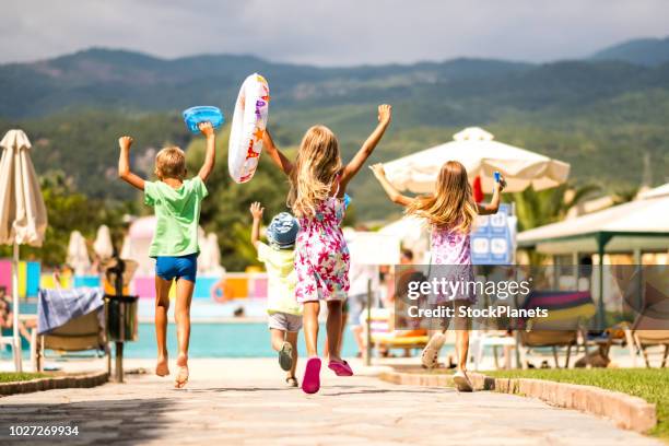 achterzijde weergave gelukkige jonge geitjes lopen naar het zwembad - family holidays hotel stockfoto's en -beelden