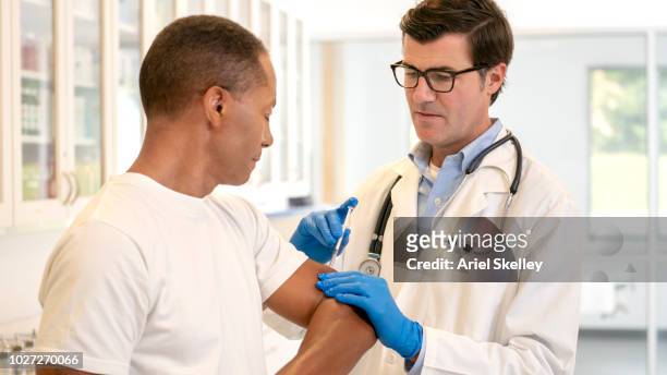 doctor giving vaccination to senior man - ariel shot stockfoto's en -beelden