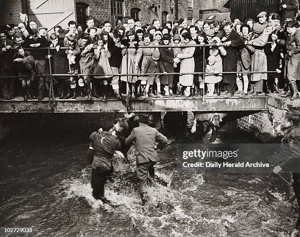 Shrovetide football at Ashbourne', 1950. A photograph of players fighting their way along Henmore Brook during the Shrovetide football match in...