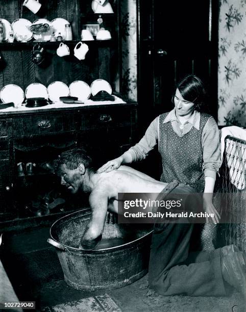 Welsh miner's wife washing her husband after work, June 1931. Photograph taken by James Jarche for the H V Morton series 'In search of Wales', .