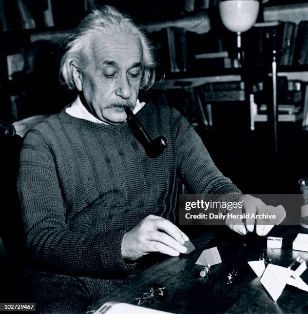 Albert Einstein at Princeton, USA, 4 February 1944. The physicist, philosopher and humanitarian Albert Einstein solving a puzzle whilst smoking a...