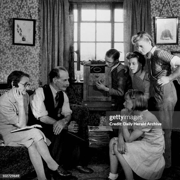 Family listening to a speech by Winston Churchill, 19 May 1945. Mr and Mrs Cooper and family tuning in their wireless to listen to a speech by Prime...