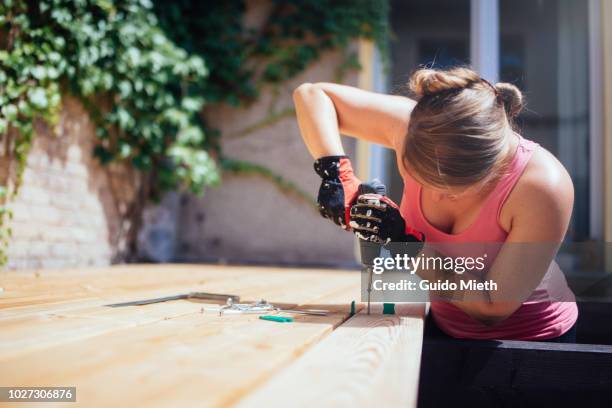 woman building garden deck in bright sunlight. - timber deck stock-fotos und bilder