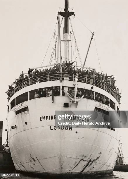 Waving passengers crowd the decks of HMT Empire Windrush as it docks at Tilbury in Essex on its arrival from Australia via Jamaica, 21st June 1948....
