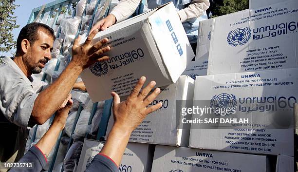 Palestinians receive food aid donated for refugees from the European Union and the World Food Programme and distributed by the United Nations Relief...