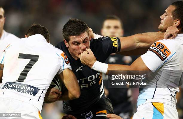 Chris Heighington of the Tigers is tackled by Bodene Thompson of the Titans during the round 18 NRL match between the Wests Tigers and the Gold Coast...