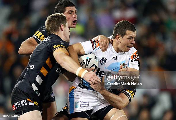 Greg Bird of the Titans is tackled during the round 18 NRL match between the Wests Tigers and the Gold Coast Titans at Campelltown Sports Stadium on...