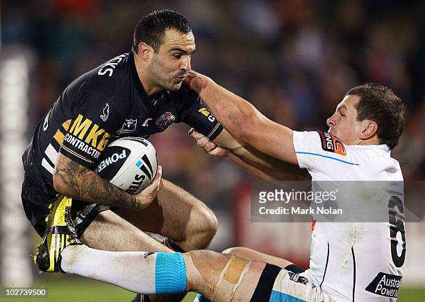 Wade McKinnon of the Tigers is tackled by Greg Bird of the Titanas during the round 18 NRL match between the Wests Tigers and the Gold Coast Titans...
