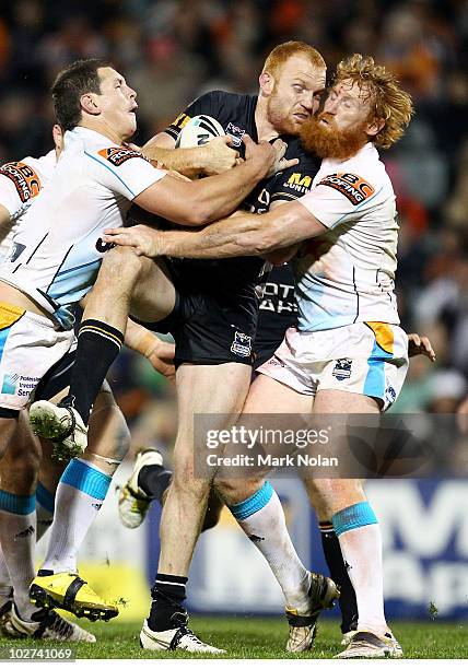 Keith Galloway of the Tigers is tackled by Greg Bird and Brad Meyers of the Titans during the round 18 NRL match between the Wests Tigers and the...