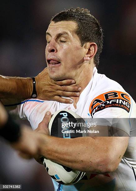 Greg Bird of the Titans is tackled high during the round 18 NRL match between the Wests Tigers and the Gold Coast Titans at Campelltown Sports...