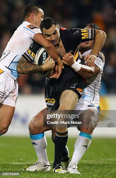 Wade McKinnon of the Tigers is tackled during the round 18 NRL match between the Wests Tigers and the Gold Coast Titans at Campelltown Sports Stadium...