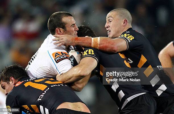Anthony Laffranchi of the Titans is tackled during the round 18 NRL match between the Wests Tigers and the Gold Coast Titans at Campelltown Sports...