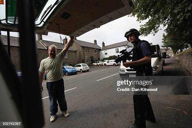 Police officer stops traffic as part of the ongoing search for Raoul Moat on July 9, 2010 in Rothbury, England. Police continue to search the village...