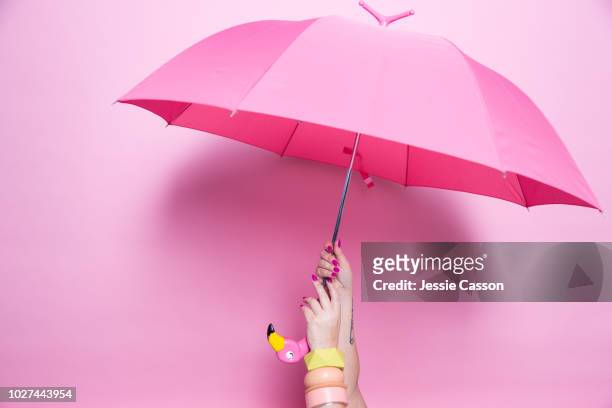 a pedicured hand holds a pink umbrella against a pink background - paraplu stockfoto's en -beelden