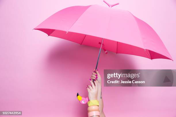 a pedicured hand holds a pink umbrella against a pink background - umbrella stock pictures, royalty-free photos & images