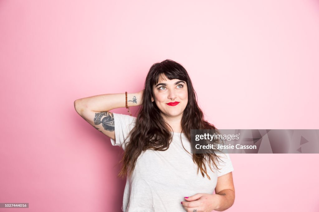 Portrait of a Woman with tattoos and red lipstick against a pink background