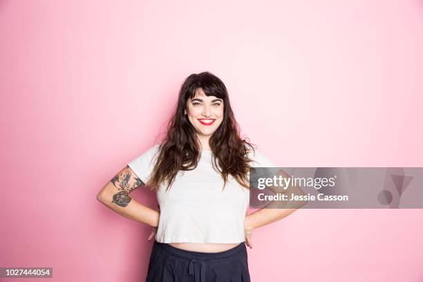 portrait of a woman with tattoos and red lipstick against a pink background - people studio shot stock pictures, royalty-free photos & images