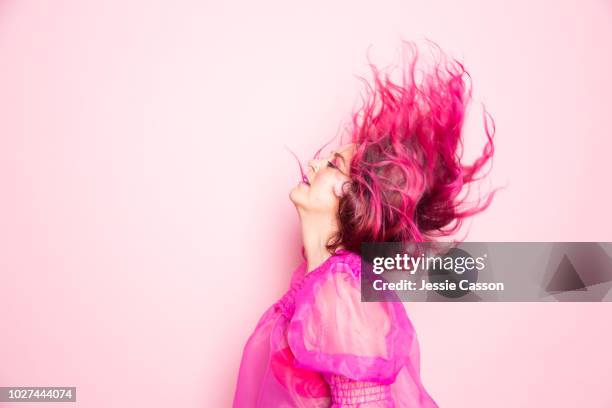 a woman with pink hair throws her head back - shot against a pink background - toned image 個照片及圖片檔