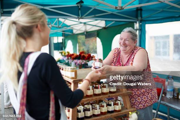 woman serving customer on local market stall. - shop seller stock-fotos und bilder