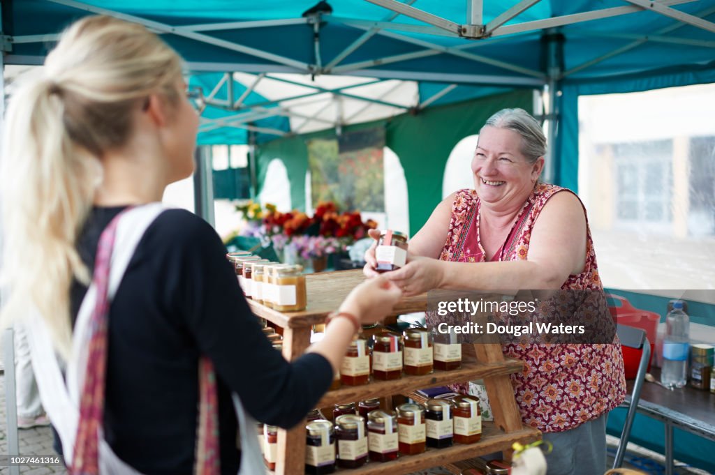 Woman serving customer on local market stall.