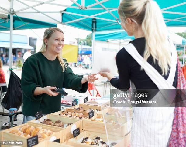 woman selling homemade cakes on a local market and serving customer. - cake sale stock-fotos und bilder