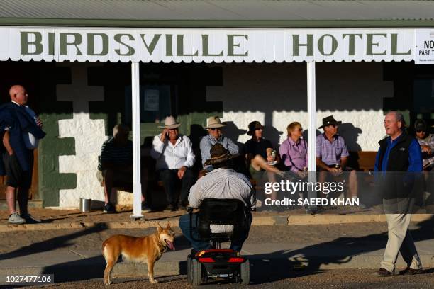 This picture taken on August 31, 2018 shows people enjoying beer at sunset outside the 134-year-old Birdsville Hotel in outback Queensland's...