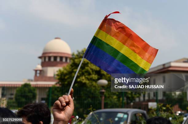 An Indian member of the lesbian, gay, bisexual, transgender community waves a flag outside the Supreme Court building as crowds gathered to celebrate...