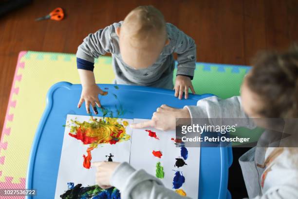 a baby boy finger painting with his mother. - nanny stock pictures, royalty-free photos & images