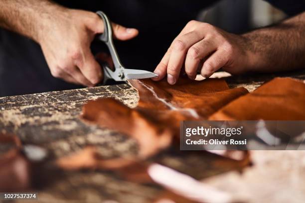 close-up of man cutting leather in workshop - materiale di pelle animale foto e immagini stock