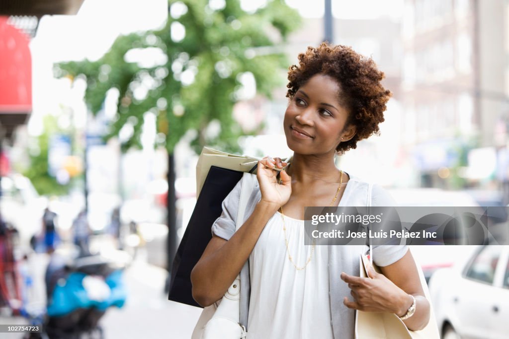 Black woman carrying shopping bags in city