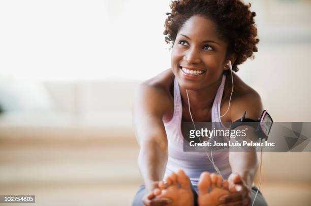 black woman stretching and listening to mp3 player - vita attiva foto e immagini stock