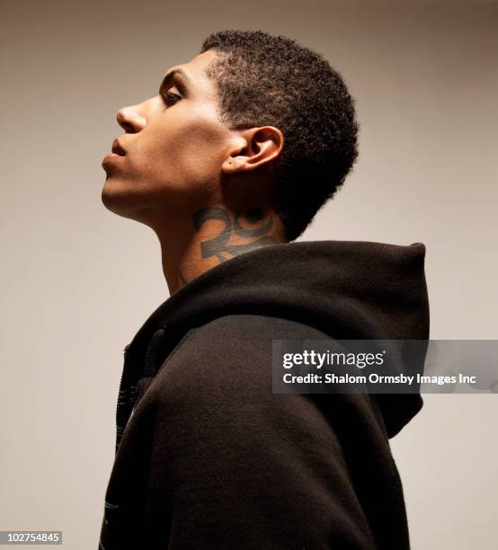 mixed race man with tattoo wearing hooded sweatshirt - side profile man fotografías e imágenes de stock