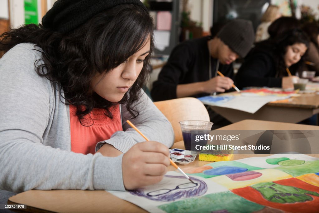 Hispanic girl painting in art class