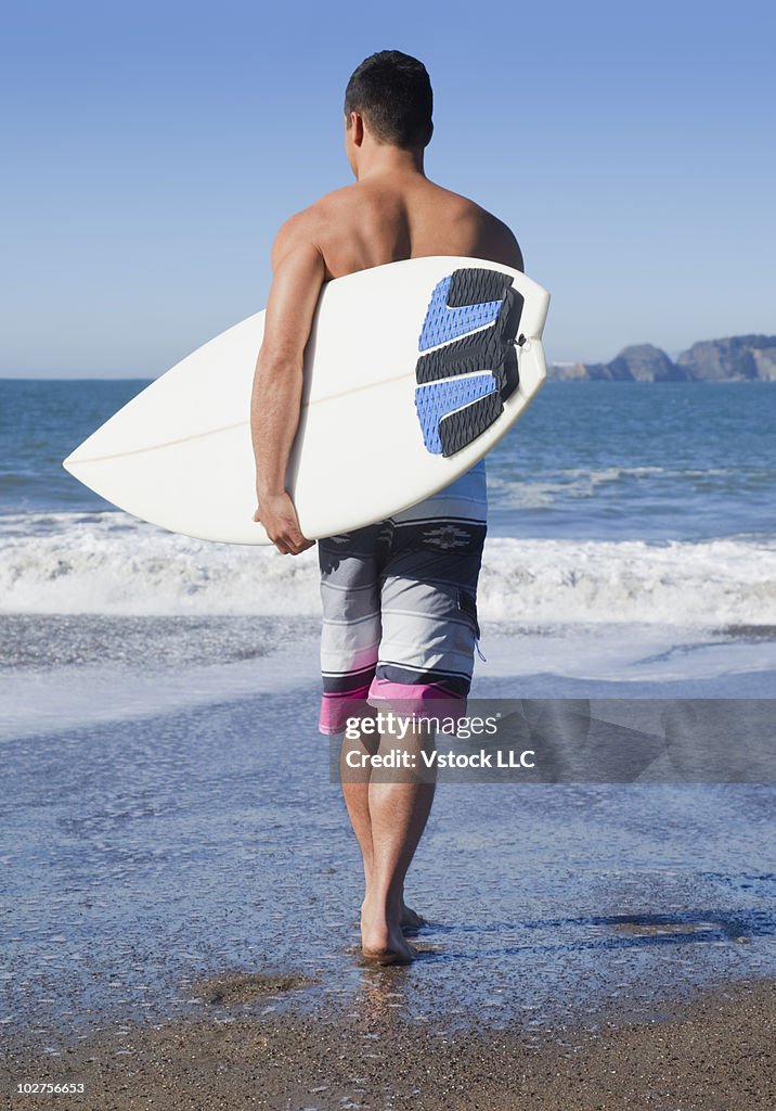 Man walking into the ocean with his surfboard