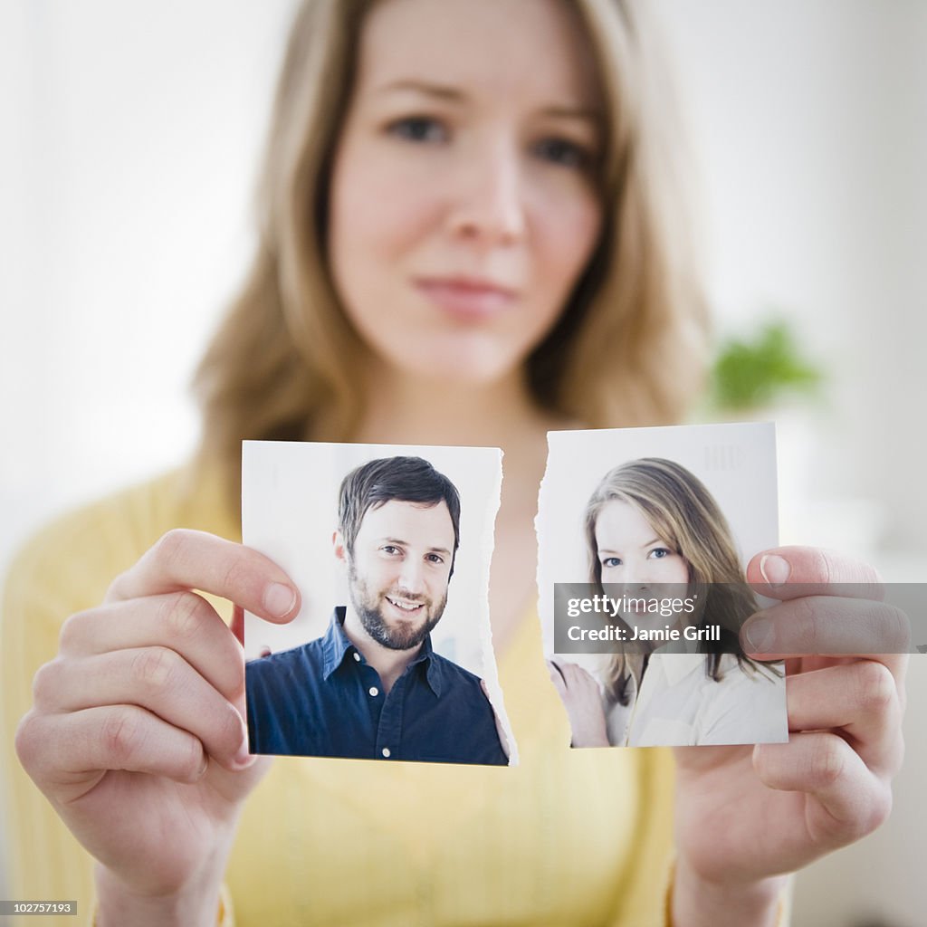 Woman holding torn photograph