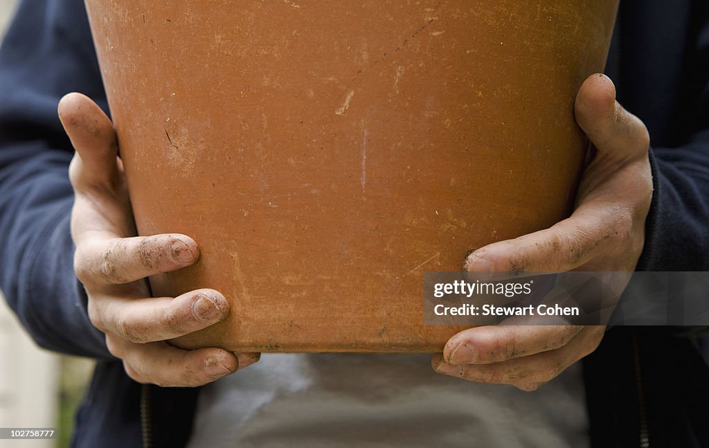 Hands holding clay pot