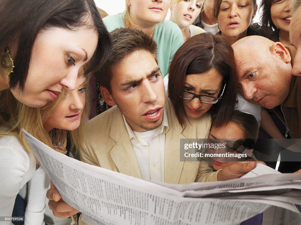 Group of people reading one newspaper