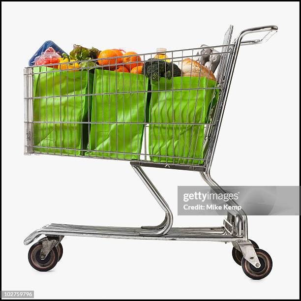 grocery cart full of bags of groceries - shopping cart fotografías e imágenes de stock